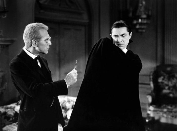 a man brandishes a crucifix at Bela Lugosi as Dracula