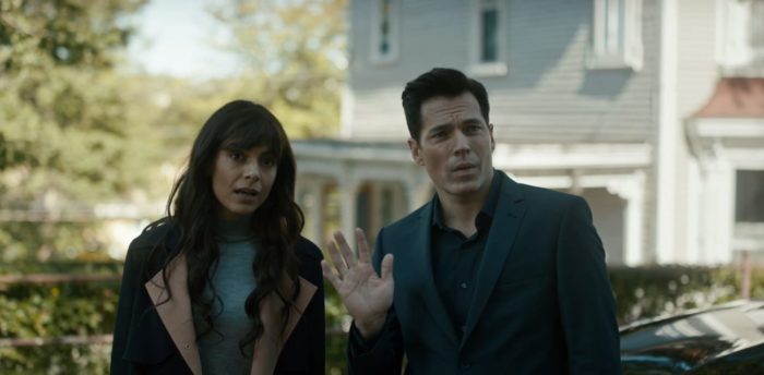 Luke waves to an off camera character while standing next to Megan