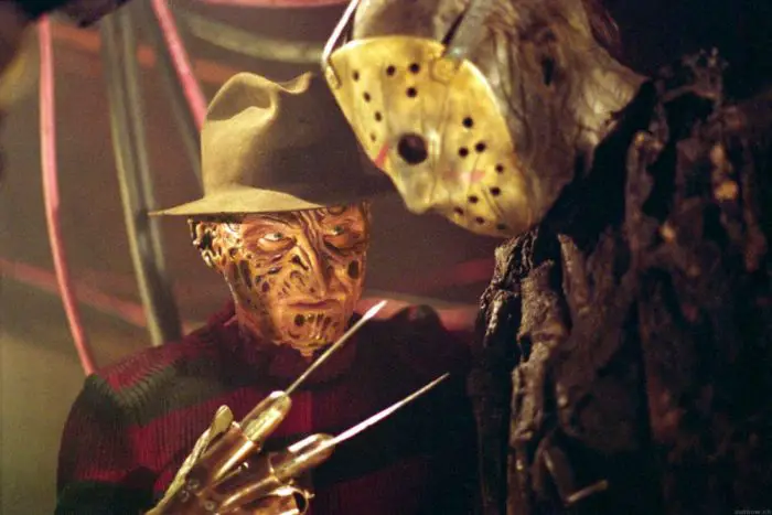 Freddy looks at a seemingly mentally defeated Jason with his bladed glove pointed at him.