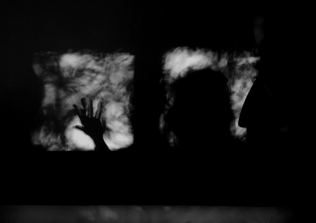 A silhouette of a person stands at a window.
