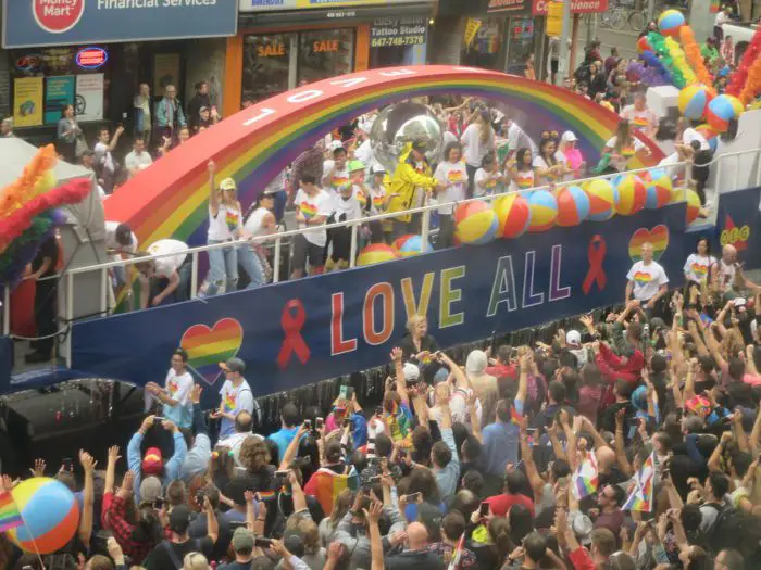 A rainbow arch and a crowd of people line the streets during Toronto Pride 2018