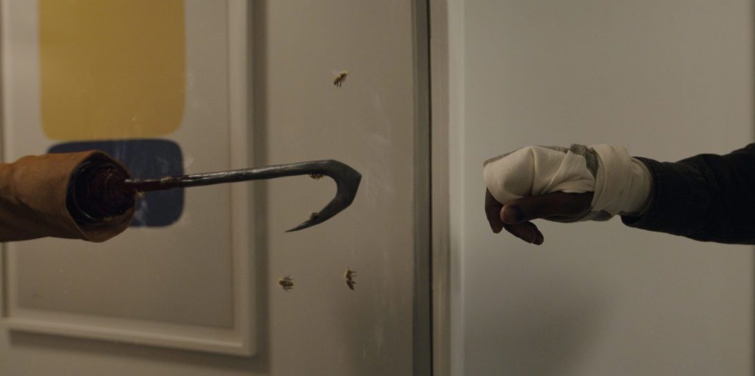 Anthony McCoy (Yahya Abdul-Mateen II, right) reaches toward a reflection of Candyman in Candyman, directed by Nia DaCosta.
