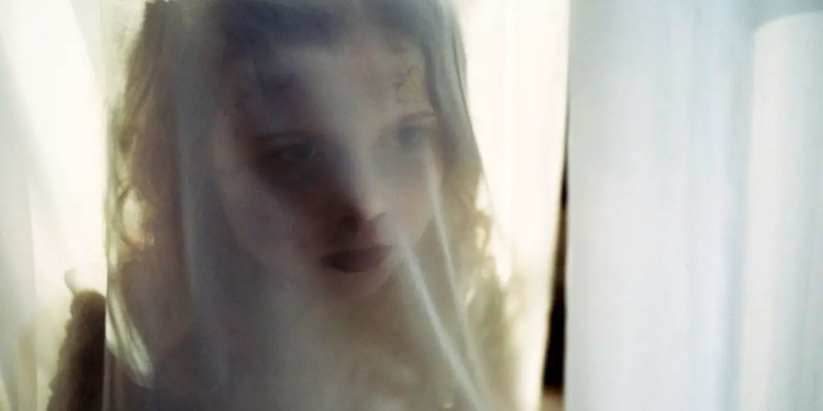 A ghostly girl seen through a thin curtain