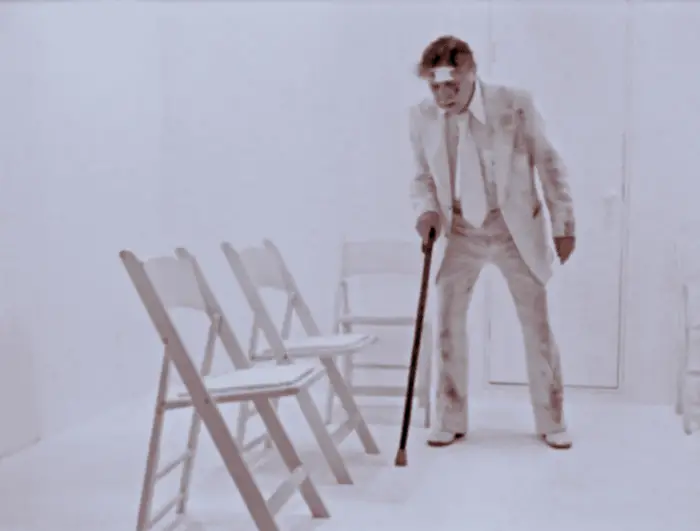 The Old Man returns to the white room from the beginning of the film, exhausted and depressed after the day's events