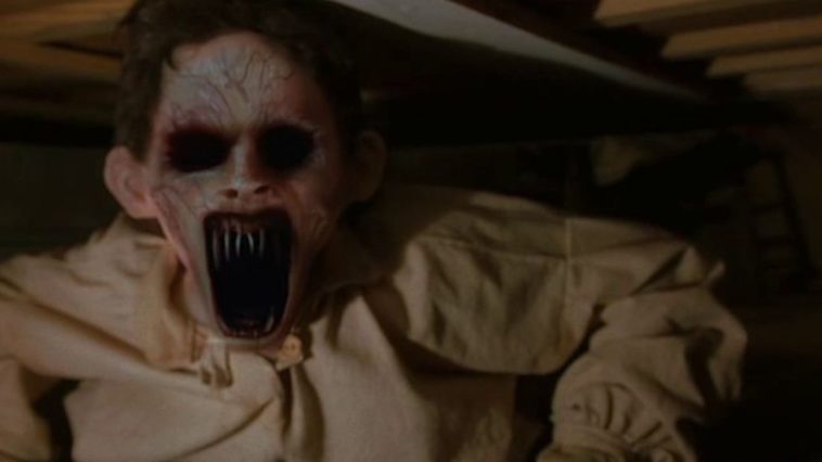 A ghoul with black eye sockets, purple veins, and razor sharp teeth peers out from beneath a bed in Dead Birds.