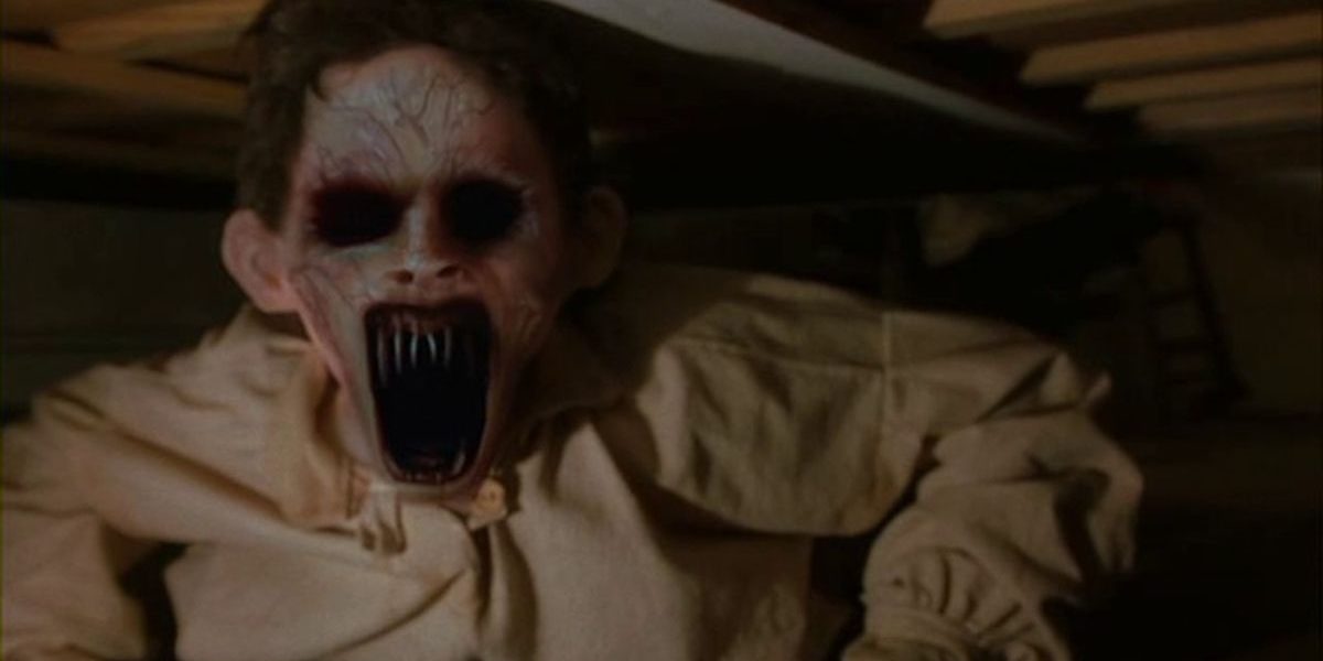 A ghoul with black eye sockets, purple veins, and razor sharp teeth peers out from beneath a bed in Dead Birds.