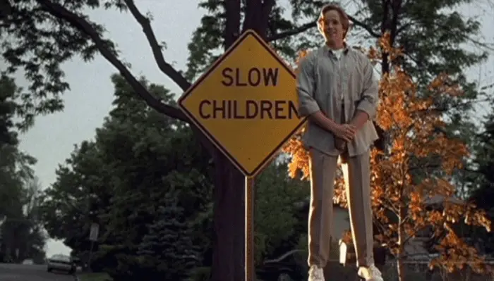 A ghost boy floats next to a sign reading "Slow Children" in a suburban setting