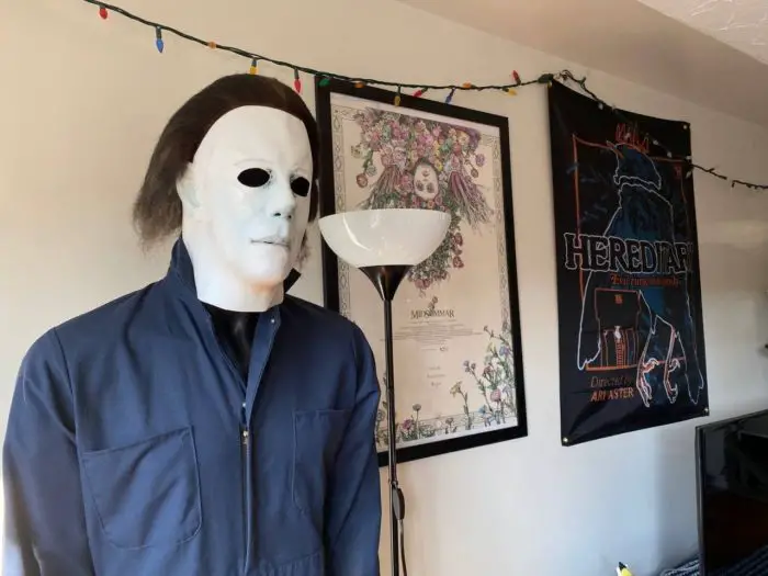 A mannequin dressed as Michael Myers stands in front o a wall with a Midsommar poster and a Hereditary wallscroll