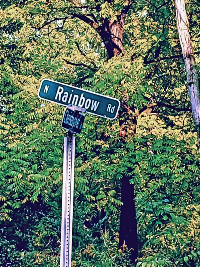 A crooked street sign reading Rainbow Road
