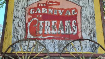 Weathered sign reminiscent of a carnival billboard announces "Carnival Freaks"