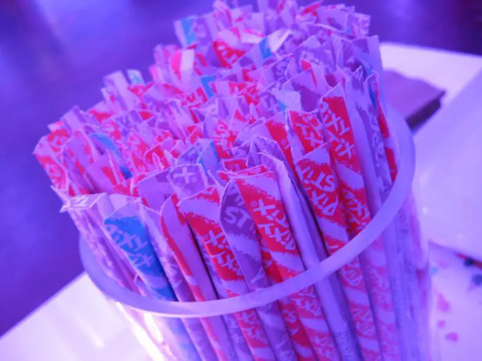 A glass filled with straws covered with decorative wrappers.