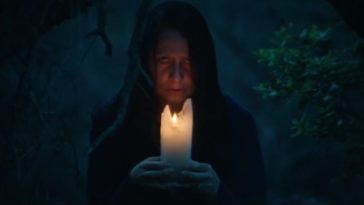 The Boogeywoman holds a candle up to her face