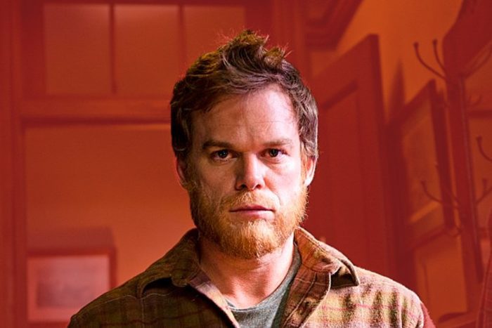 The titular character from the series Dexter, seen from the shoulders up looking intensely toward the camera, his hair slightly unkempt, a light beard on his face, wearing a flannel shirt unbuttoned at the top.