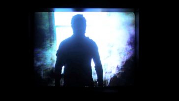 A man cast in shadow stands before a window, bathed in intense blue light