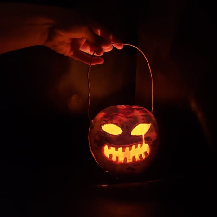 Carved turnip jack-o'-lantern lit by a candle inside, glowing in the dark.