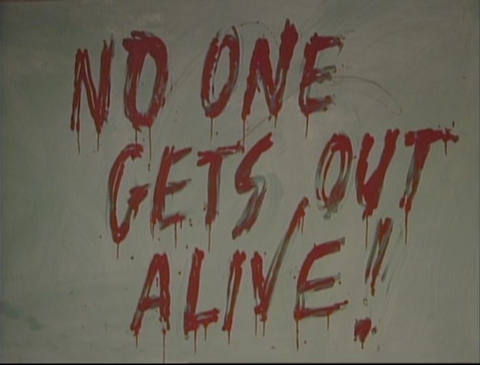 A message written on a chalkboard that reads "No one gets out alive!"
