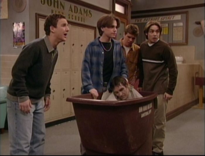 Cory, Shawn, Jack, and Eric stand over the janitors dead body that's been stuffed into a garbage bin.