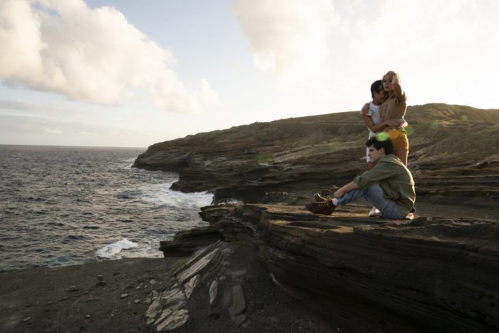 "Lennon", Margot, and Dylan sitting on a rock formation looking out at the ocean