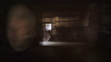 Blurred image of a dark room with the image of a translucent women in a white dress.