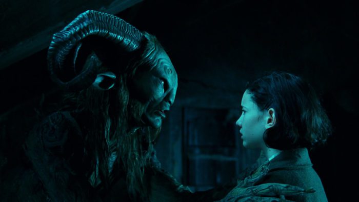 A faun-like creature is looking at a young girl with dark hair, holding her by the shoulders.