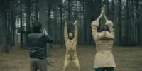 Dennis, Roger and Mia raise their arms to the sky while standing in the wods