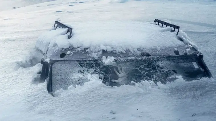 a hand is pressed against the glass of a car window, surrounded by snow and ice