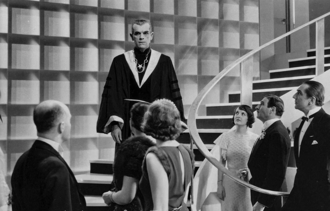 Karloff's character walking down stairs in front of other people