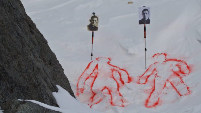 two silhouettes of bodies are outlined in red in the snow. marked above them are photographs of the victims
