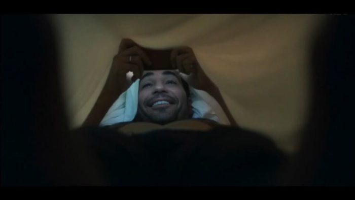 Paco lays under the covers giggling during his live chat with Elena while they watch Padre Vergara on the cameras