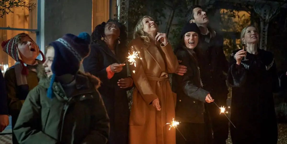 The cast of Silent Night stand outside in heavy winter coats lighting sparklers and looking at the sky.