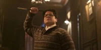 Guillermo in a patterned sweater holding a stake above his head dramatically