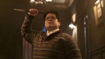 Guillermo in a patterned sweater holding a stake above his head dramatically