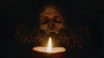 Albrun's shrine, featuring her mother's skull decked in garlands and a candle