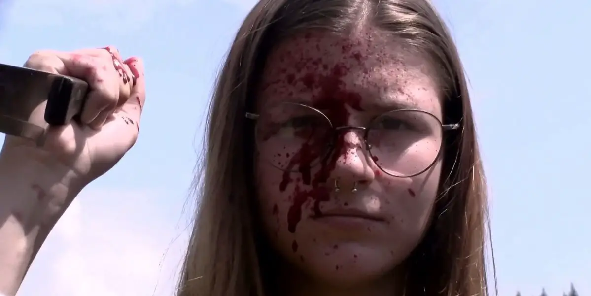 a young girl with a blood-soaked face holds a knife in Honeycomb