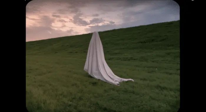 A scene from A Ghost Story , as the ghost walks through an expansive empty field 