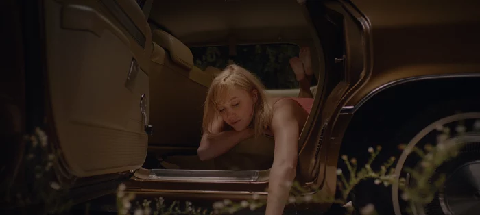 Jay lying down in a car and sticking her arm out
