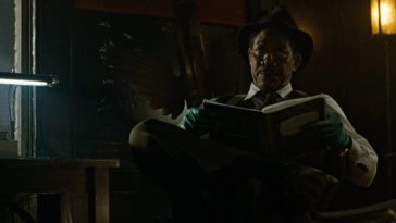 Morgan Freeman sits in a chair reading a book