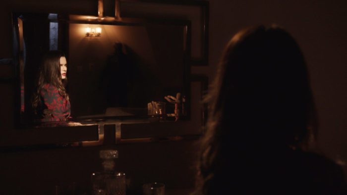 A woman seeing a dark figure in her mirror