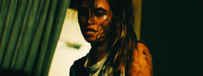 A young woman appears bloodied with hair running down the middle of her face in The Seed
