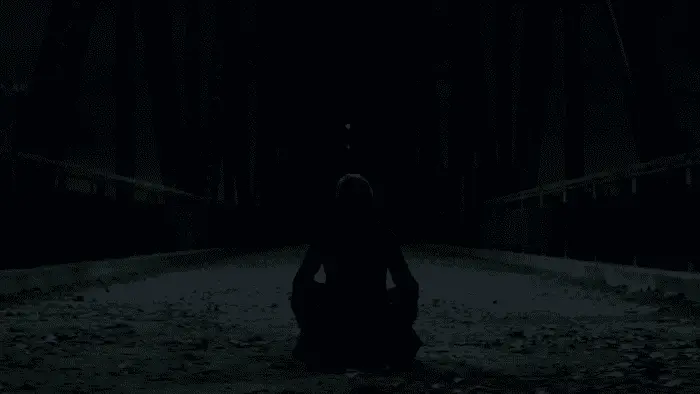 A teenage girl sits on a bridge in the middle of the night