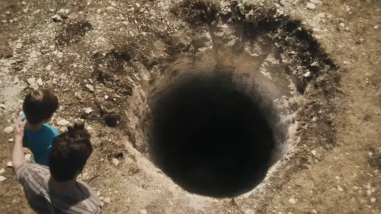A father and son look into a mysterious hole