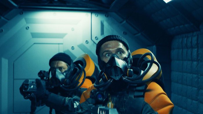 People in space suits and masks looking scared