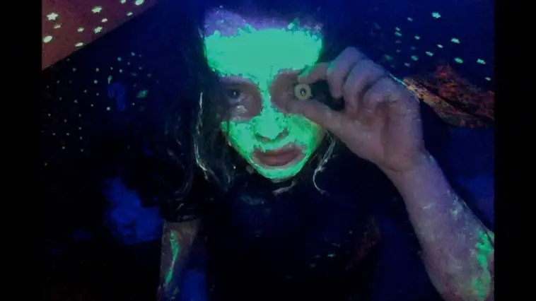 Covered in glow in the dark paint, and holding an eyeball in front of hers, Casey stares down the barrel of the camera