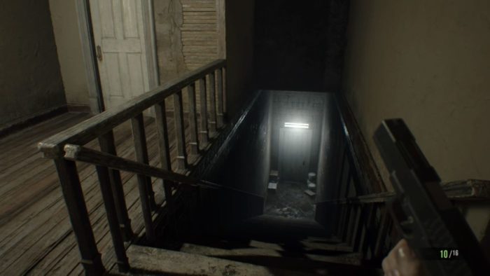 A staircase with a single fluorescent light above the door at the bottom