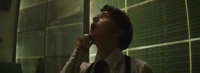 Robin looks up while holding a phone receiver to her ear in The Bunker Game
