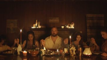 The cast of Hell is Empty sits at a candlelit table resembling DaVinci's The Last Supper
