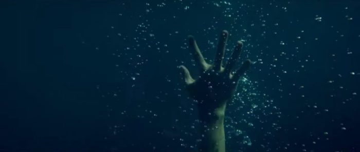 A hand rises up through the water in Monstrous