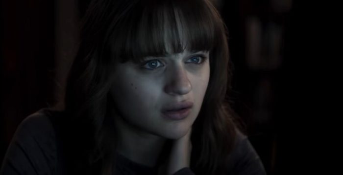 A closeup of girl ina dark room with the light of either a TV or computer screen on her face.