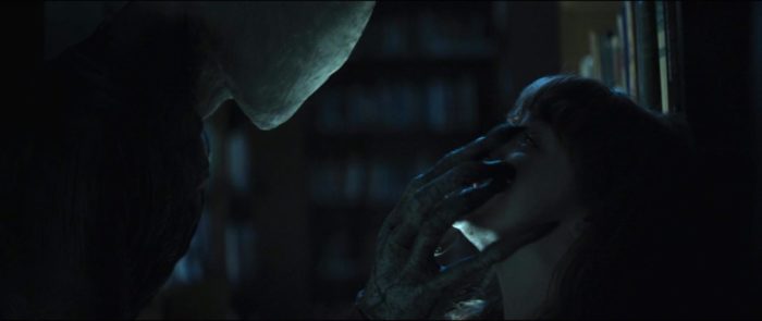 A humanoid being grabs a girl and puts his hand over her face.