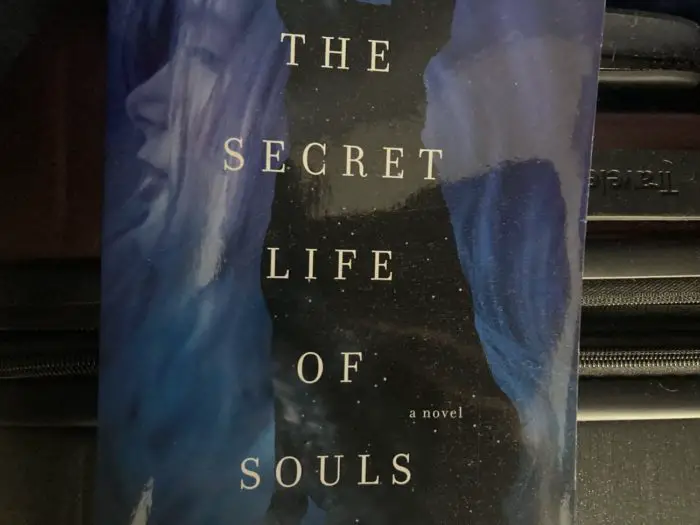 Cover for the Secret Life of Souls has the title over a dog's silhouette and a young girl's face in the background 